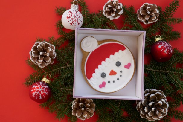 圣诞和新年。圣诞姜饼和饼干。寒假糖果。盒子里的雪人姜饼，甜筒，红色的节日球和在明亮的红色背景上的冷杉树枝图片下载