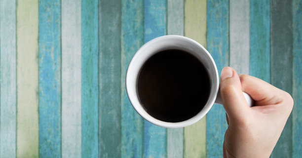 白咖啡杯柄，健康的黑咖啡，上面有一个古董木桌，该饮料有助于塑形，降低胆固醇，预防心脏病。图片下载