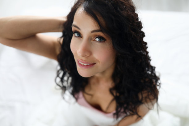 美丽的女人肖像对白色的床的背景图片下载