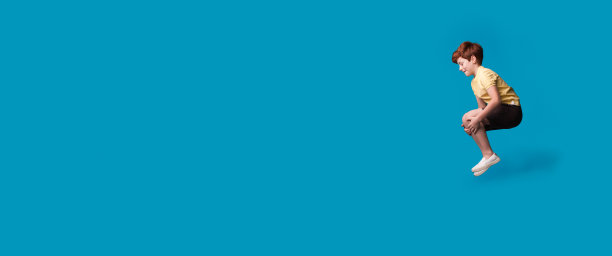 姜白种人男孩手势在游泳池中跳跃，而微笑和促进在一个蓝色工作室自由空间的东西图片下载