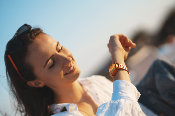 年轻女子看她的手表在日落图片下载