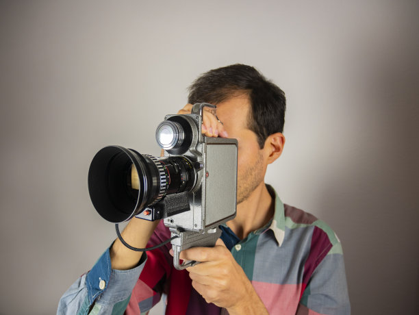 摄影师的肖像与旧电影摄影机。复古的摄像机。年轻的摄影师，电影导演，带着一台旧的电影摄影机。图片下载