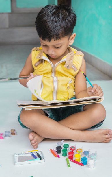 快乐的小男孩用彩色水彩画。图片下载