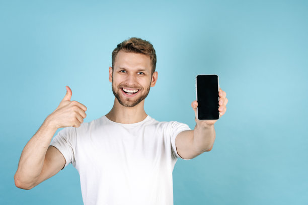 年轻人竖起大拇指，拿着现代智能手机图片下载
