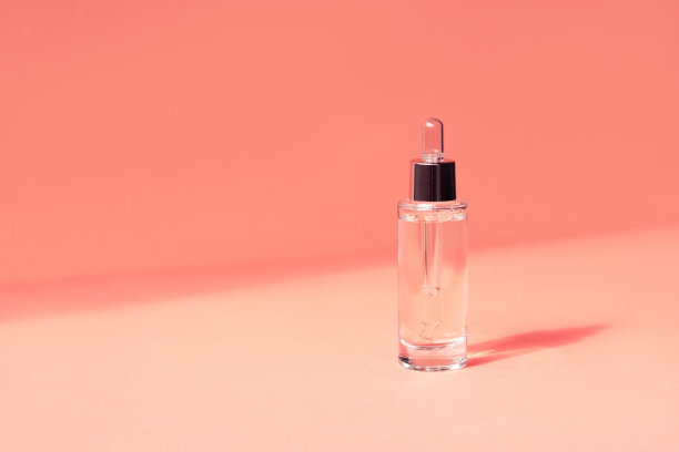 玻璃瓶化妆品血清精致珊瑚背景。图片下载