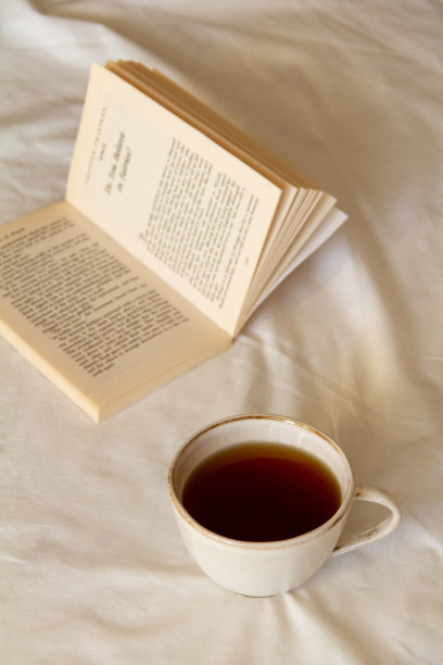早上一杯茶，白色的床上放一本书图片下载