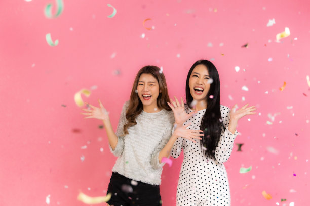 两个可爱的亚洲女人的肖像在圣诞节帽子看孤立的相机在粉红色的背景。迷人的亚洲女人微笑在圣诞节，新年，情人节，生日庆祝概念。图片下载