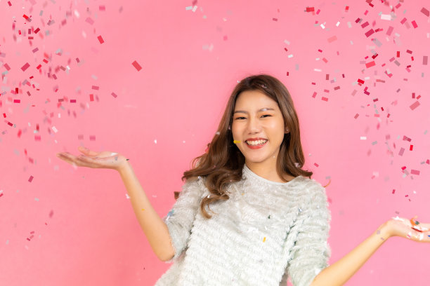 两个可爱的亚洲女人的肖像在圣诞节帽子看孤立的相机在粉红色的背景。迷人的亚洲女人微笑在圣诞节，新年，情人节，生日庆祝概念。图片下载