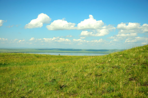 沐浴在阳光下的山谷里，有一个湖面平静的宽阔湖泊。图片下载