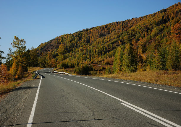 一条双车道的柏油路沿着山脊延伸，变成了一个风景如画的秋天山谷。图片下载