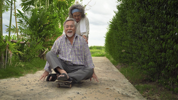 老夫妇玩滑板玩得很开心，他们回到了年轻的时候。温暖的家庭的主题。图片下载