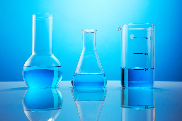 在蓝色背景下，桌子上有蓝色液体的实验室玻璃器皿。化学分析。试管》的实验。图片下载