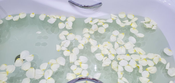 在充满水和玫瑰花瓣的浴缸中放松。放松的概念图片下载