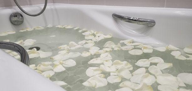 在充满水和玫瑰花瓣的浴缸中放松。放松的概念图片下载