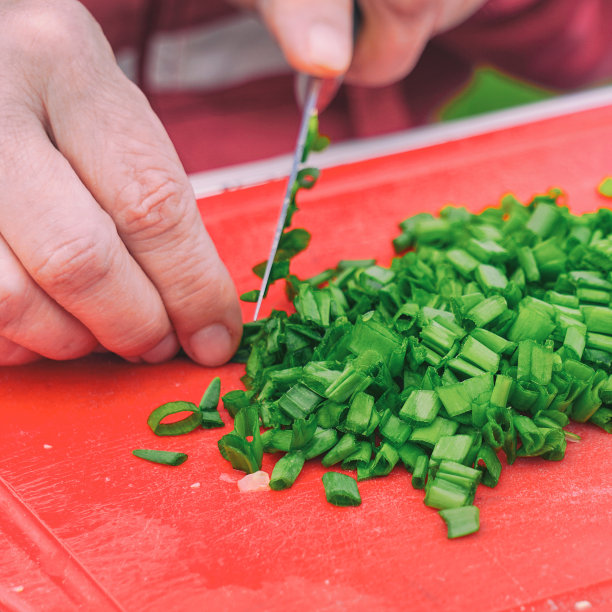 一位妇女用刀切绿洋葱图片下载