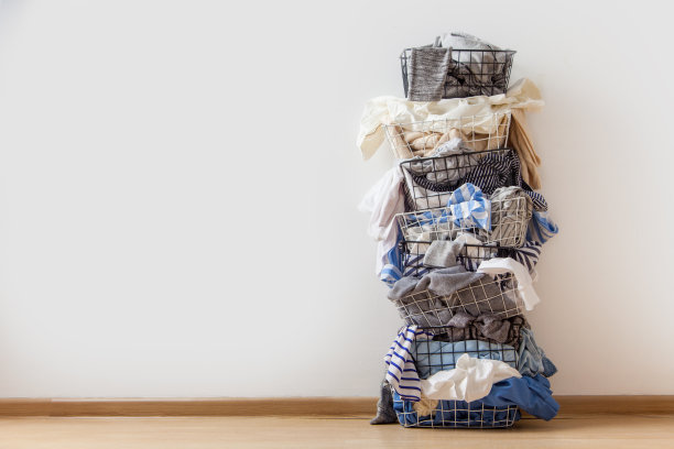 一排堆叠的金属洗衣篮，里面装满了白色背景上的衣服图片下载