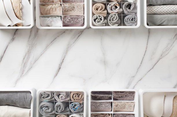 女士的内衣裤、睡衣和袜子整整齐齐地叠好，放在衣柜的抽屉隔板上，放在白色的大理石桌上图片下载