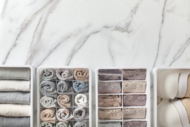 女士的内衣裤、睡衣和袜子整整齐齐地叠好，放在衣柜的抽屉隔板上，放在白色的大理石桌上图片下载