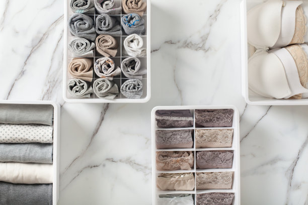 女士的内衣裤、睡衣和袜子整整齐齐地叠好，放在衣柜的抽屉隔板上，放在白色的大理石桌上图片下载