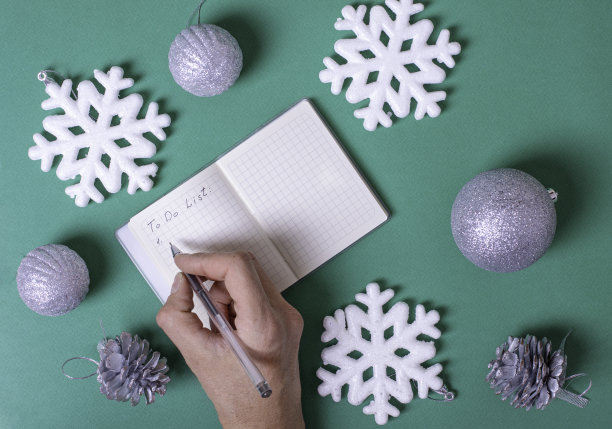 一个女人的手在一个空白的笔记本上写下了一个待办事项清单，需要在圣诞节前完成图片下载