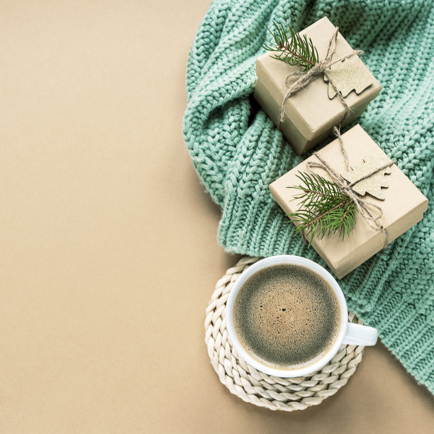 一杯咖啡和圣诞礼物上的绿色毛衣米色背景，俯视图，拷贝空间图片下载