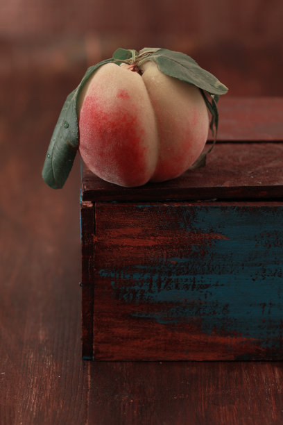 桃带着叶子，放在木桌上，质朴，垂直图片下载
