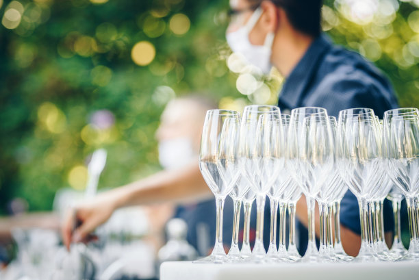 疫情期间的户外餐饮服务：戴口罩的调酒师和香槟杯图片下载