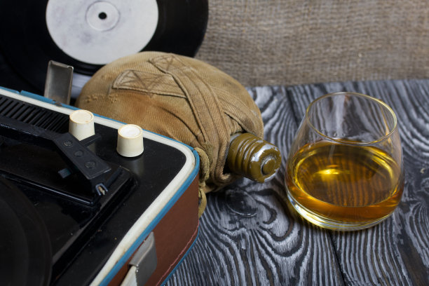 旧的转盘。旁边有一个烧瓶和一杯烈性酒。复古方设备。图片下载