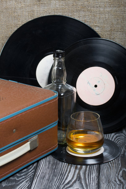 旧的转盘。旁边是一杯烈性酒和一个空玻璃瓶。复古方设备。图片下载