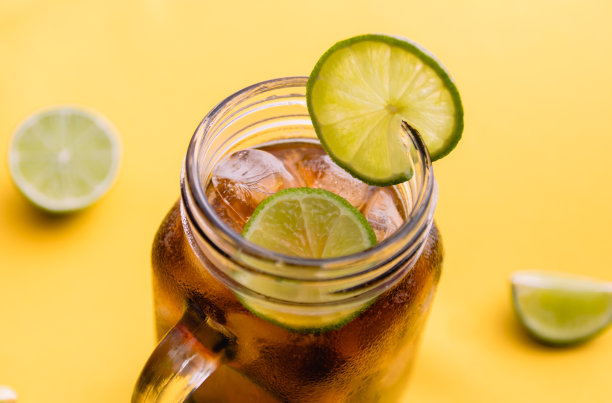 冰茶与柠檬片mason罐子在明亮的黄色背景图片下载