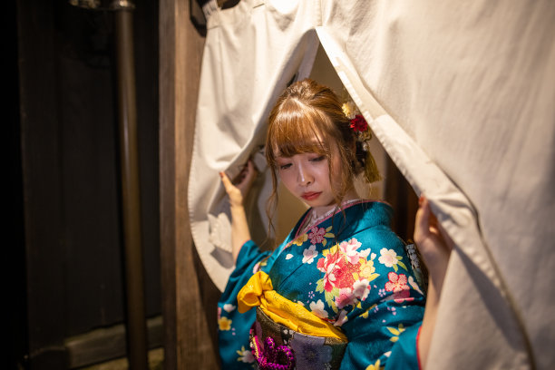 晚上，穿着Furisode和服的年轻女子走过Noren入口图片下载