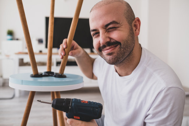 可爱的男人手里拿着无线电钻眨着眼睛。图片下载