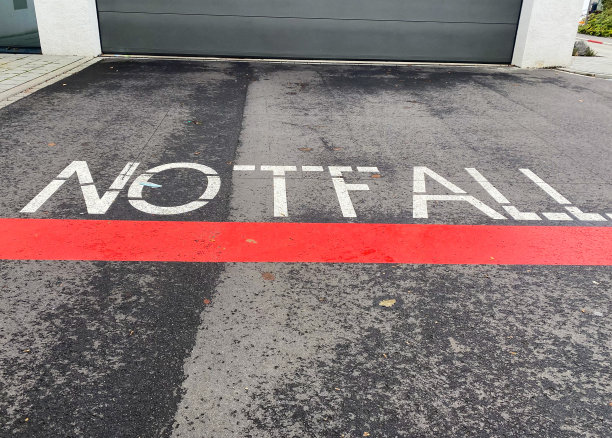 看孤立的德语单词Notfall(英文意思:紧急)与红色线漆在沥青在急诊室的入口图片下载