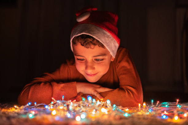 男孩在家里玩圣诞彩灯图片下载