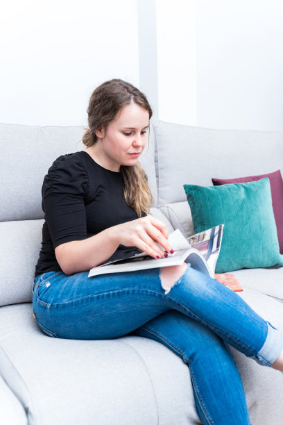 年轻女子在客厅里浏览装饰杂志。改革，生活方式和室内设计。图片下载
