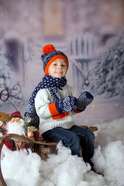 可爱的小男孩穿着冬装，在雪地里玩耍素材图片