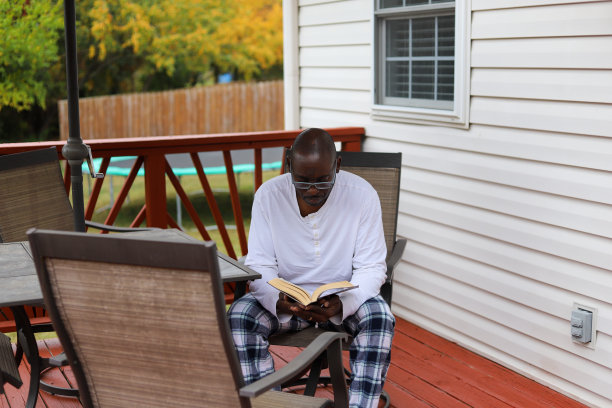 一幅非裔美国人的肖像，在秋天的早晨在露台上看书图片下载