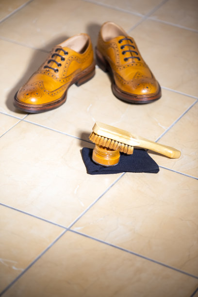 一双豪华男性全broged棕色牛津鞋。与鞋蜡和刷子一起放在地砖地板上。垂直方向图片下载
