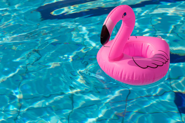 海的背景。粉红色的充气火烈鸟在游泳池的水为夏天的海滩背景。奢侈的生活方式。图片下载