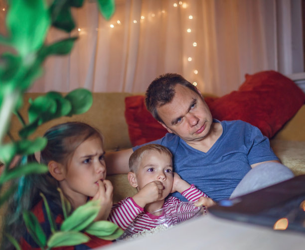 家庭电影之夜。父亲和孩子们看电影用笔记本电脑，室内生活方式图片下载