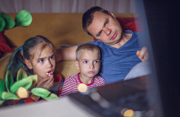 家庭电影之夜。父亲和孩子们看电影用笔记本电脑，室内生活方式图片下载