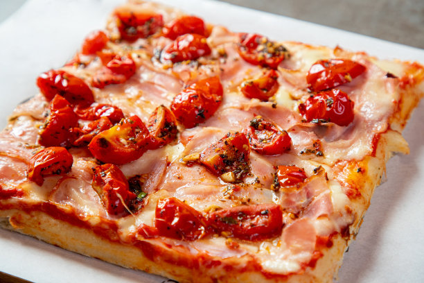 披萨切片配樱桃番茄、罗勒、帕尔玛芝士和火腿图片下载