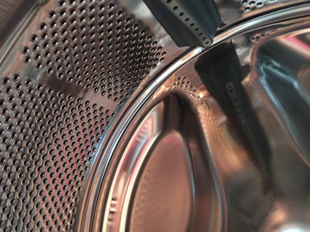 洗衣机的滚筒从里面。闪亮的金属罐，有孔和凸起。不锈钢表面带孔，由不锈钢板材制成。洗衣机的内部视图图片下载