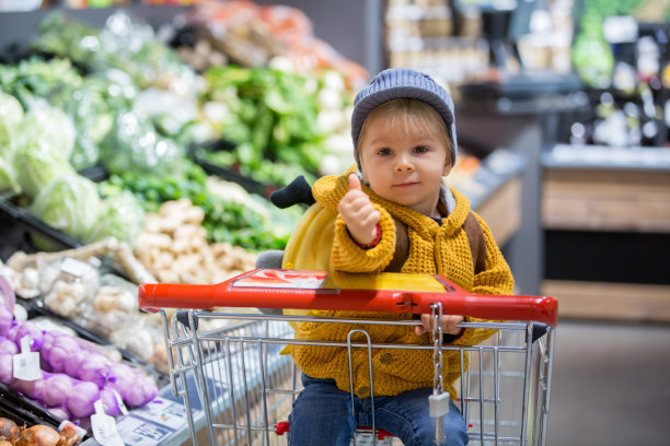 时尚的蹒跚学步的小男孩背着背包，在超市购物图片下载