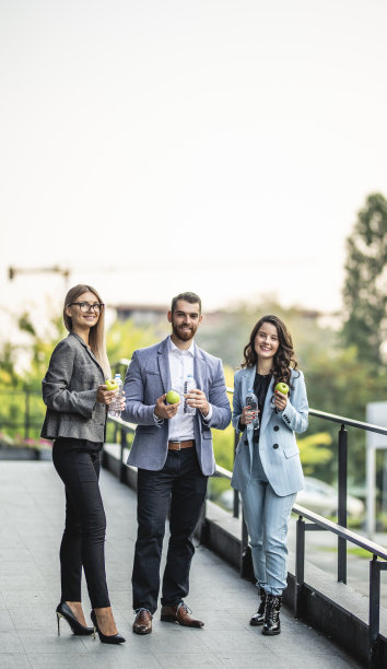 三个年轻的商人在户外休息，吃午饭，吃青苹果和喝水图片下载