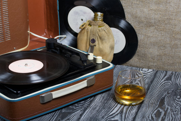 旧的转盘。旁边有一个烧瓶和一杯烈性酒。复古方设备。图片下载