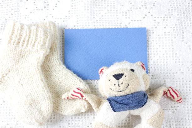 羊毛手工制作的婴儿袜子，玩具泰迪熊和地方，你的文本。新生的贺卡。图片下载