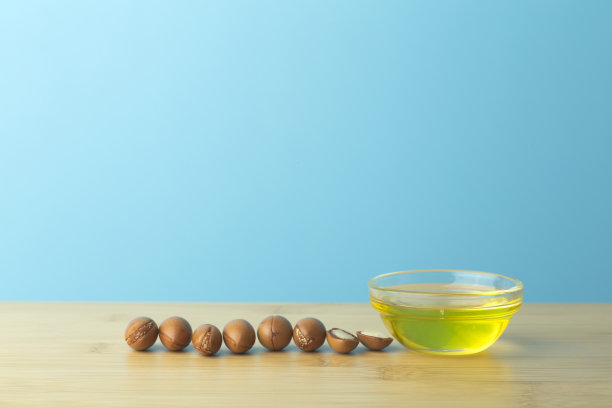 摩洛哥坚果油背景。在空荡荡的蓝色背景下，木桌上放着摩洛哥坚果和橄榄油。本空间图片下载