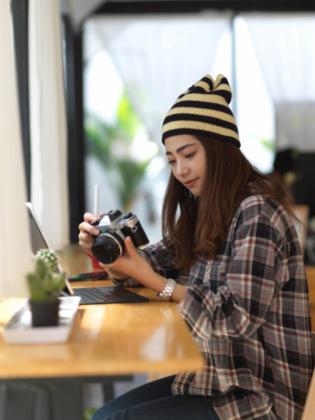 坐在咖啡馆里拿着相机的女摄影师图片下载