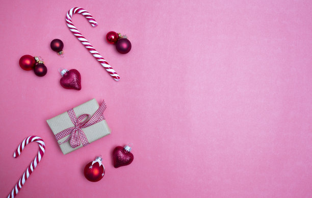 圣诞背景与礼品盒，糖果拐杖和圣诞装饰品在粉红色的背景图片下载